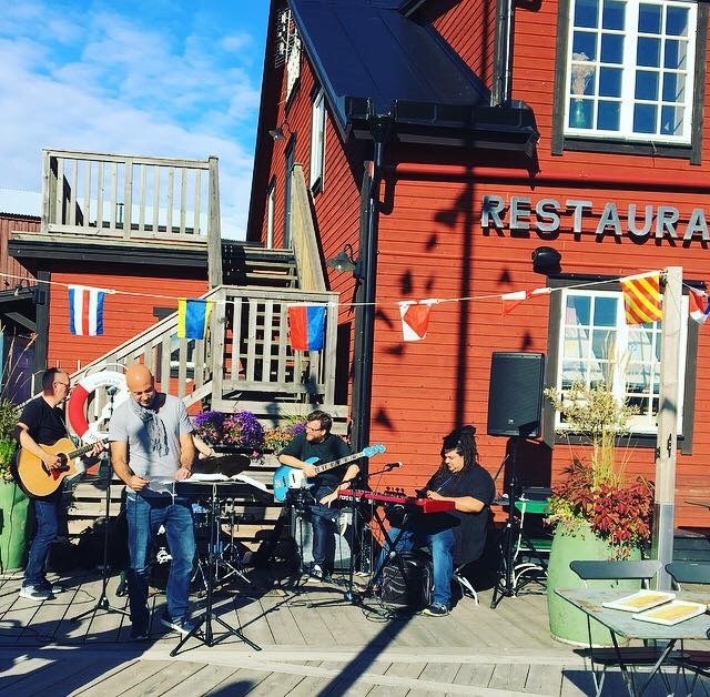 SMASH spelar akustiskt utomhus framför en röd restaurang i skärgården
